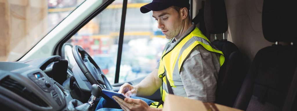 The new normal for courier drivers: Pic - Delivery driver using tablet in van with parcels on seat